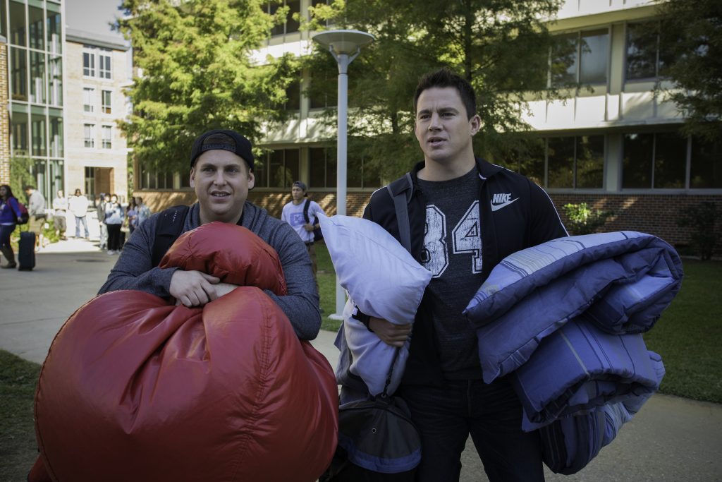 2 Guys standing and holding personal stuffs in front of the building from 22 jump street