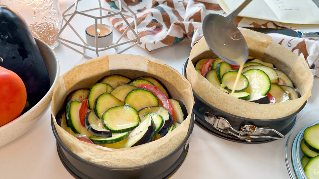 crustless spiral summer vegetables tart with zucchini eggplants and tomato pouring egg mixute